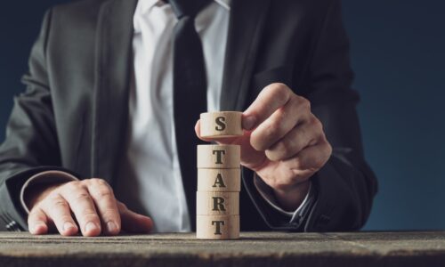 Businessman stacking wooden cut circles to assemble the word Start in a conceptual image.